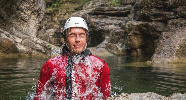 Ein Mann taucht beim Canyoning im Salzkammergut aus dem Wasser