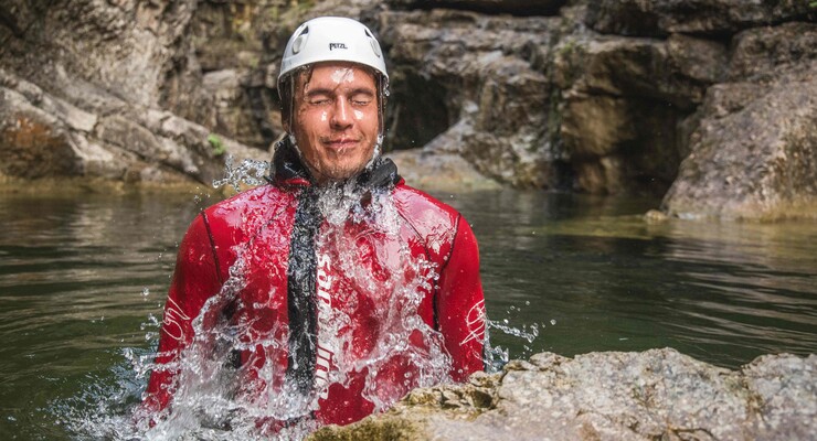 Ein Mann taucht beim Canyoning in der Strubklamm aus dem Wasser